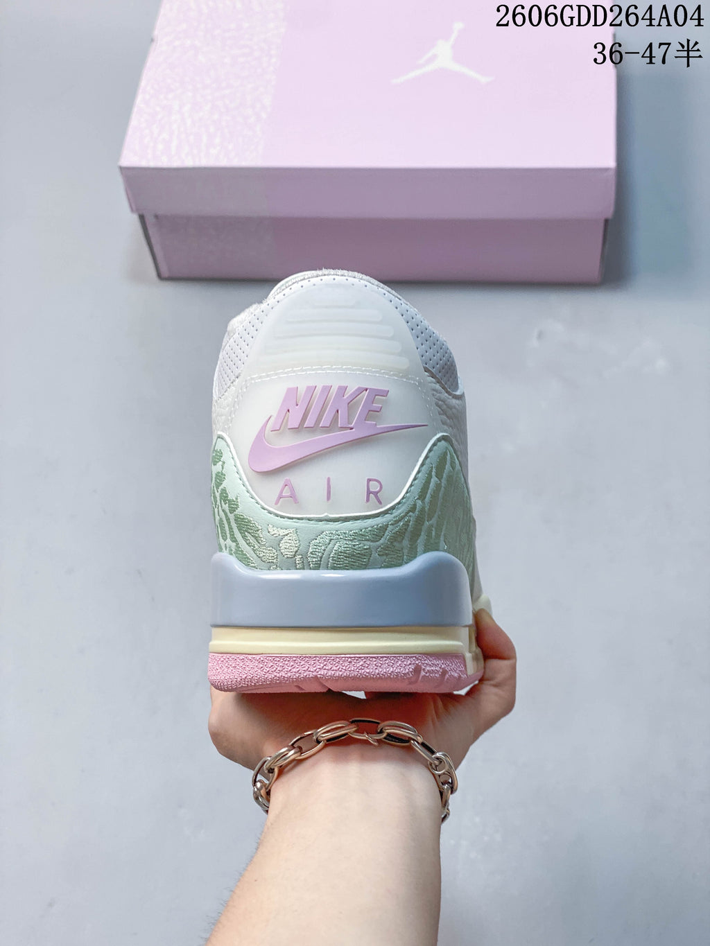 Rear view showing patterned heel panels, pink branding details, and the shoe box.