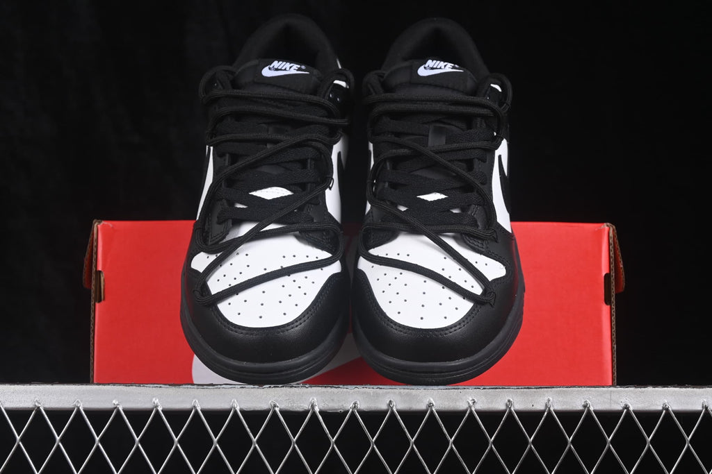 Front view of black and white sneakers positioned on a red Nike shoe box.