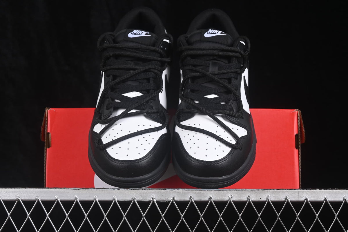 Front view of black and white sneakers positioned on a red Nike shoe box.