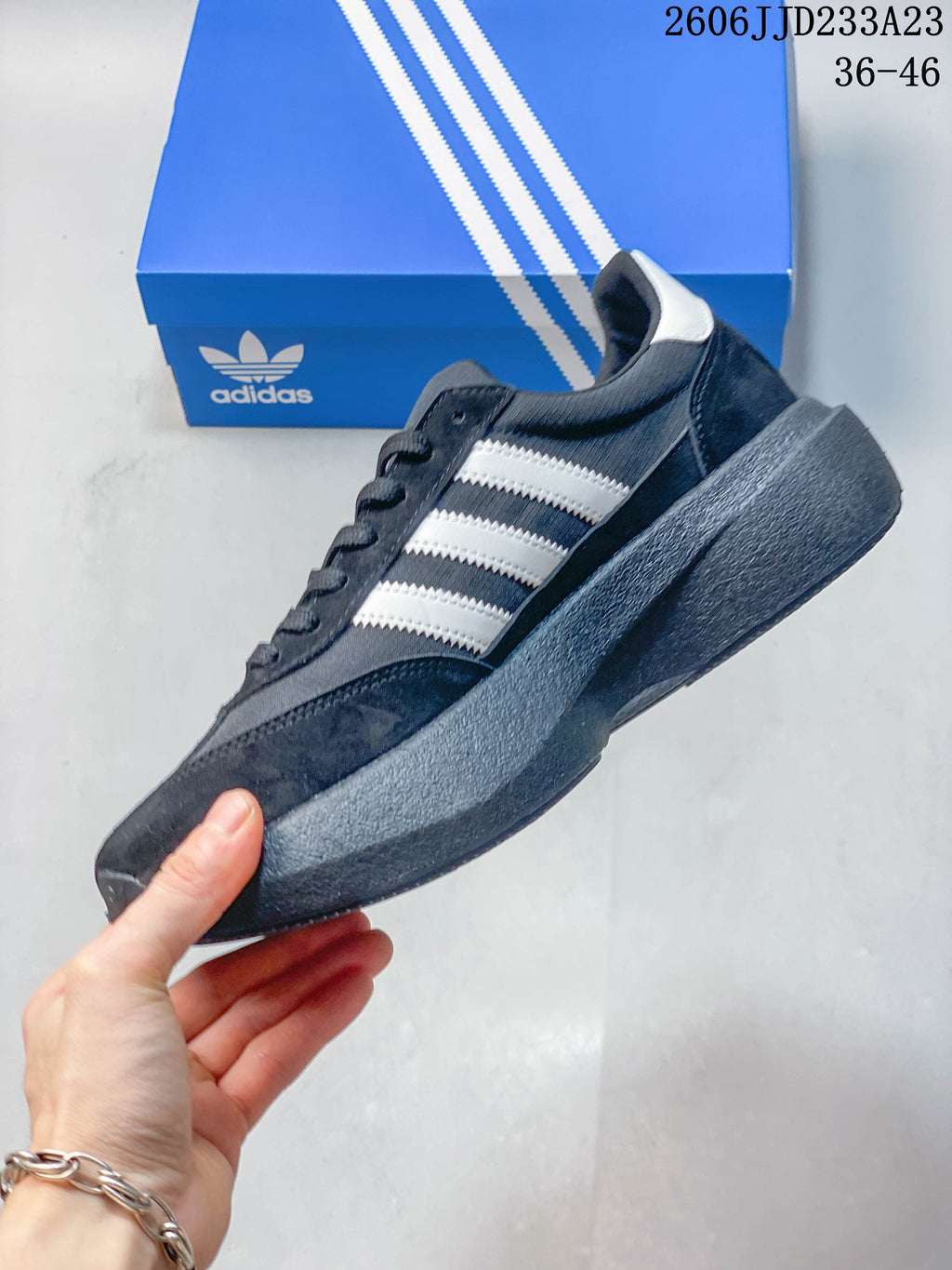 Side view of a charcoal gray sneaker with white stripes and a chunky gray sole