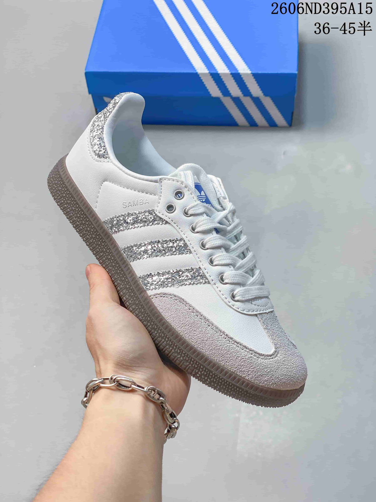 Side view of a white low-top sneaker with sparkling silver stripes and gray textured sole