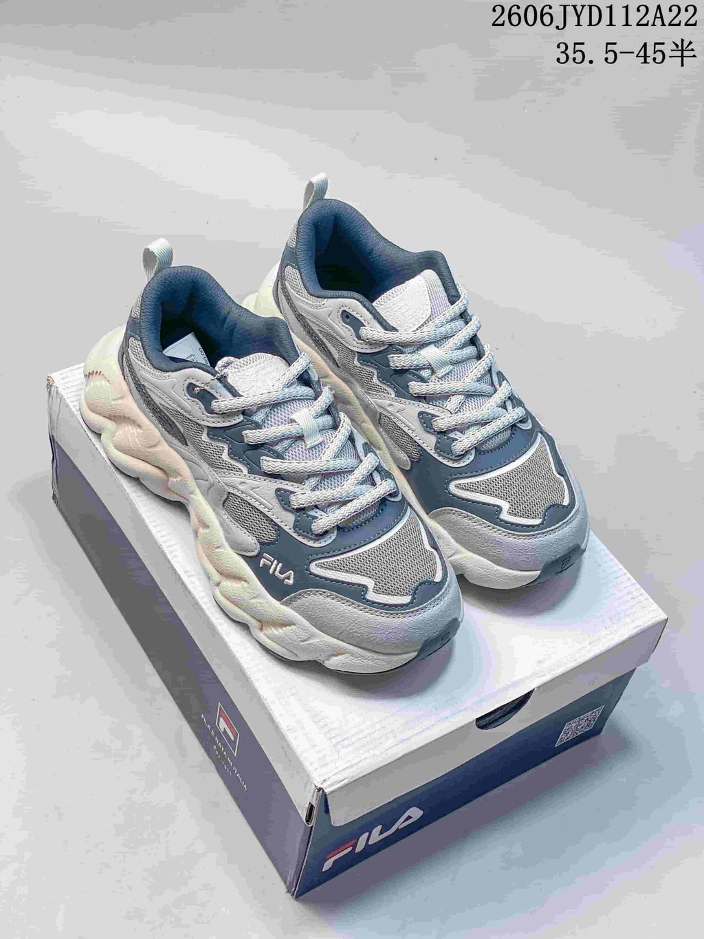 Light gray FILA sneakers with blue-gray accents and a chunky sculpted sole.