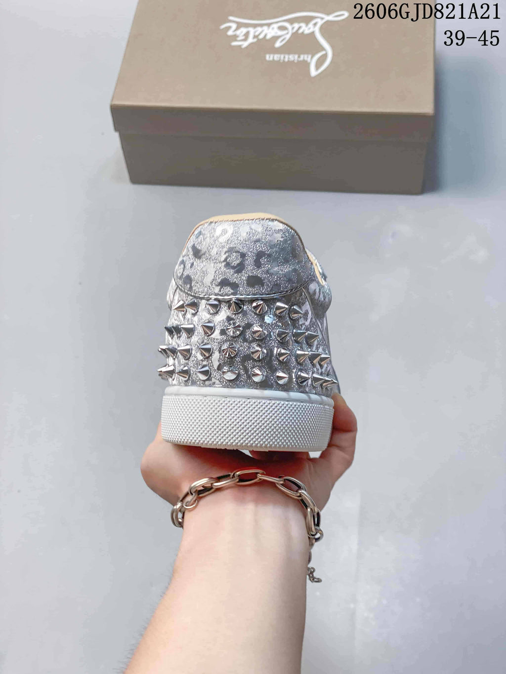 Rear view showing metallic studs on the heel of a silver sneaker