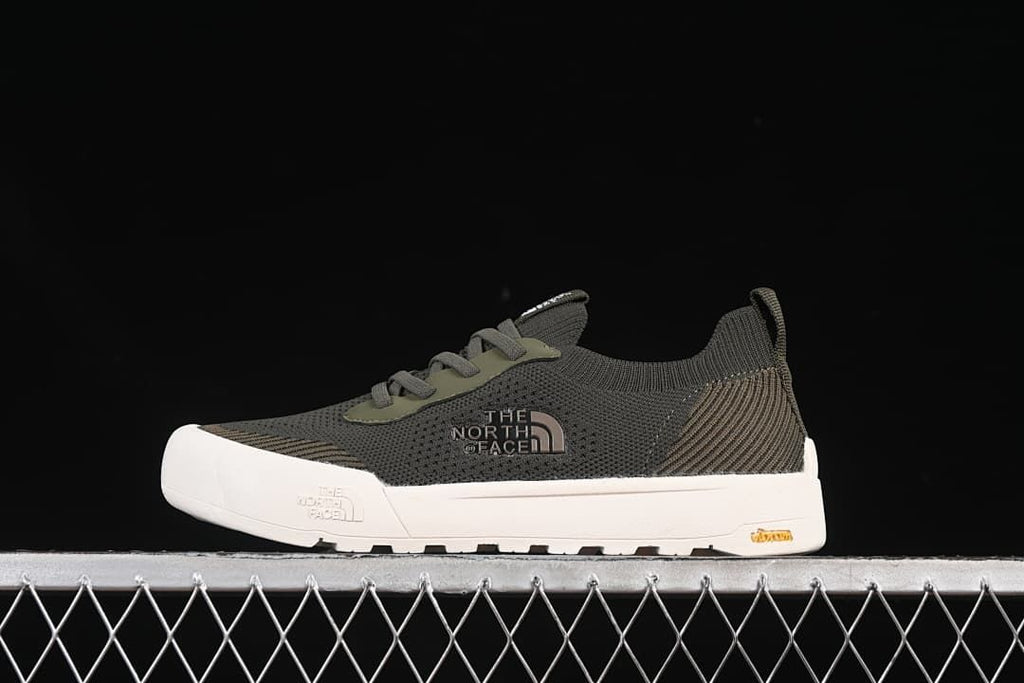 Side view of an army green and dark gray low-top sneaker with a white sole