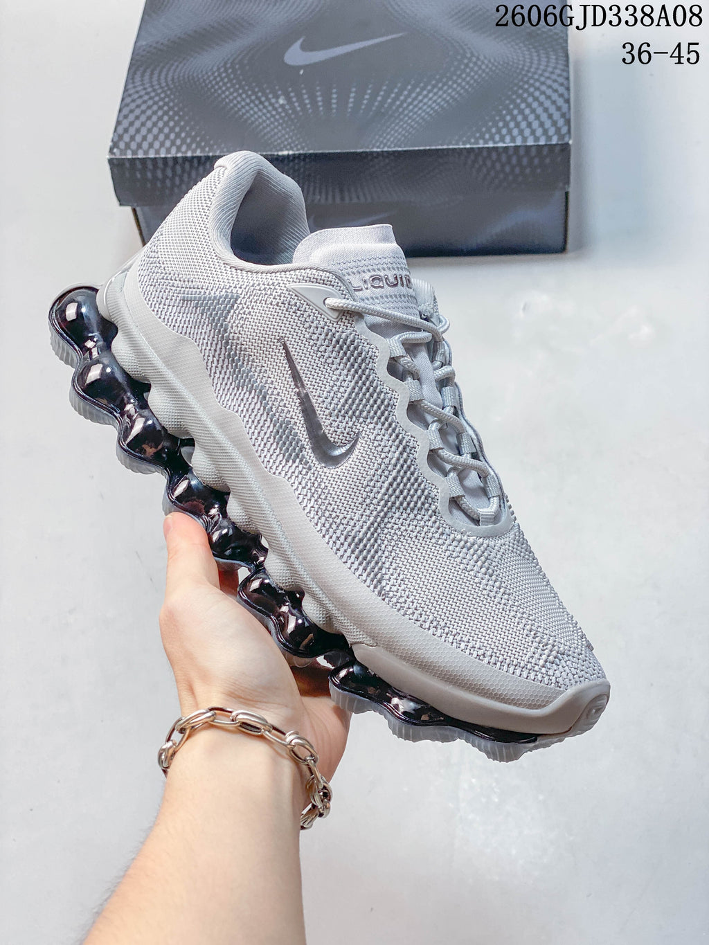 Angled side view of a light grey Nike Air Liquid Max sneaker with a dark segmented outsole
