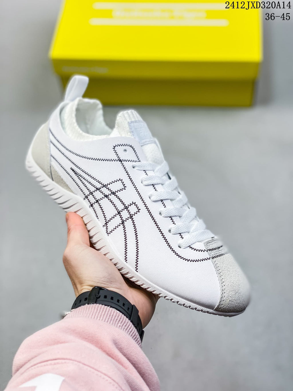 Angled side view of the white low-top sneaker with black stitched details and gray accents