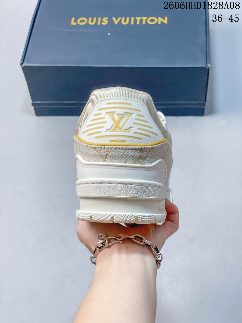 Rear view of a white sneaker with gold-tone heel detailing.