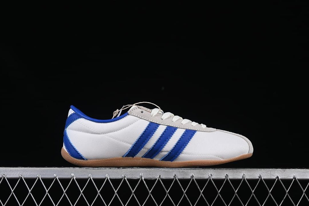 Side profile of the white sneaker with blue stripes and gum outsole