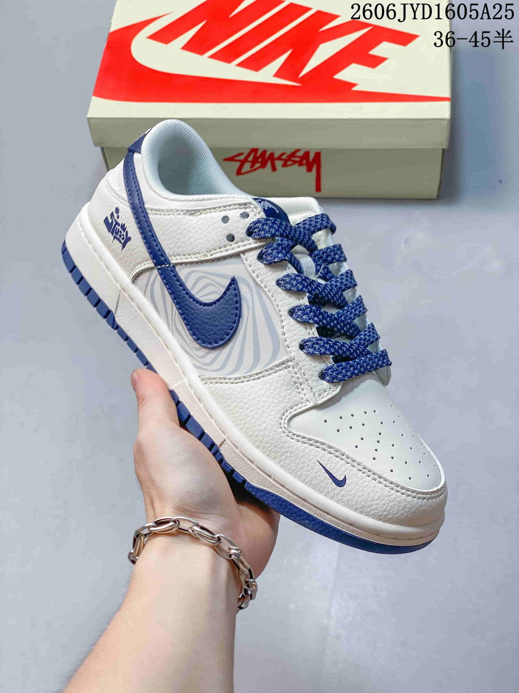 White low-top sneaker with blue overlays, blue laces, and a wavy gray side panel