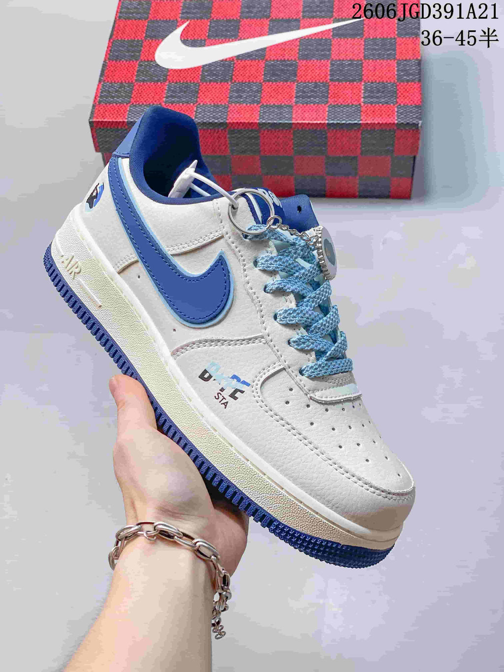 Close-up of a white low-top sneaker with blue Swoosh detail, blue laces, and a lace charm.