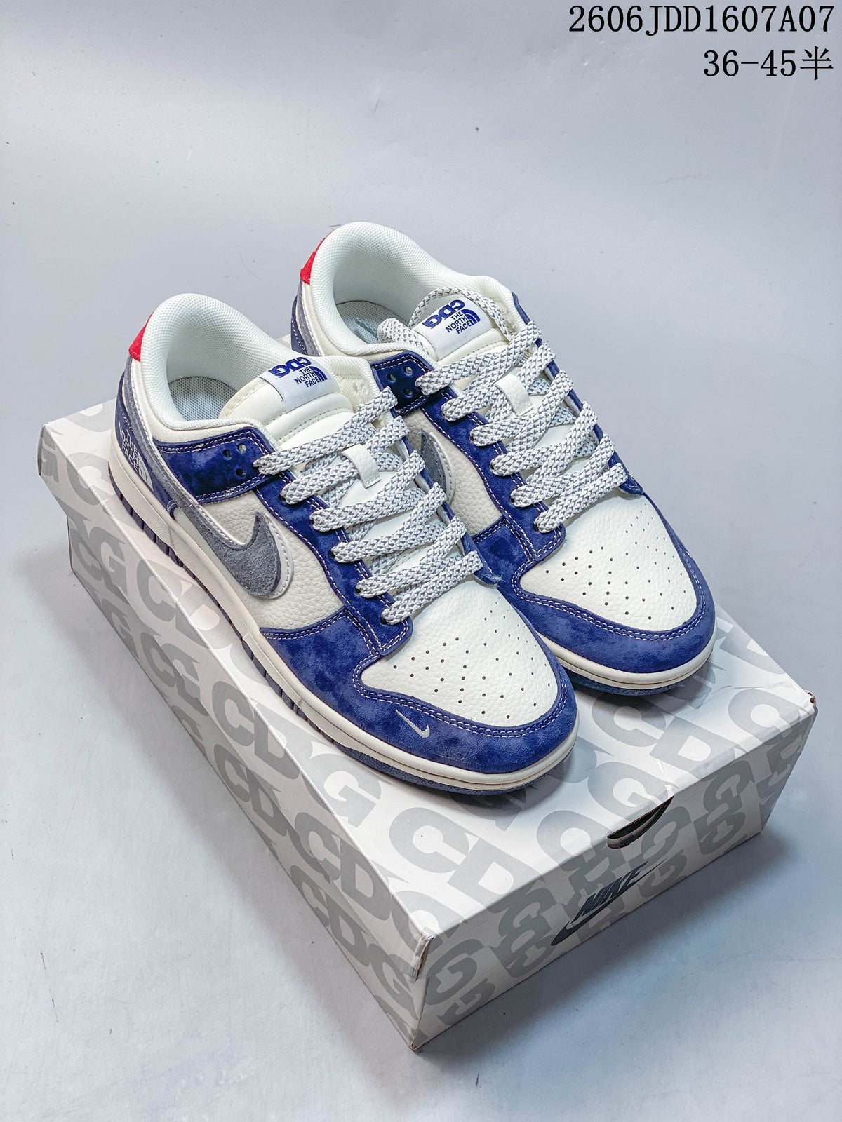 Pair of navy and white low-top sneakers with grey side swooshes on a patterned box.