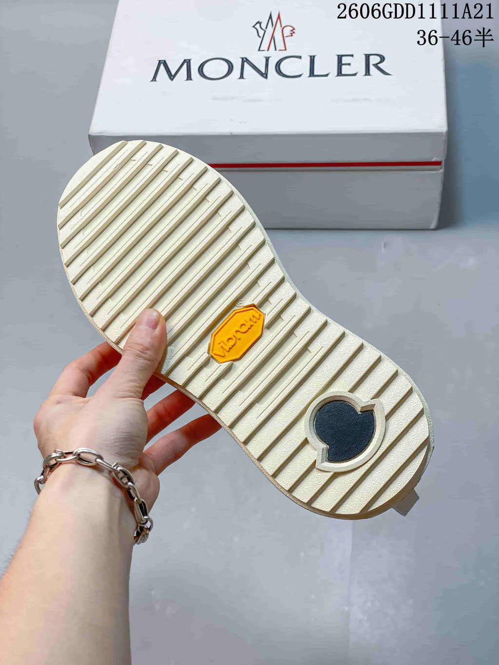 Underside of a Moncler sneaker showing ridged tread and logo detail