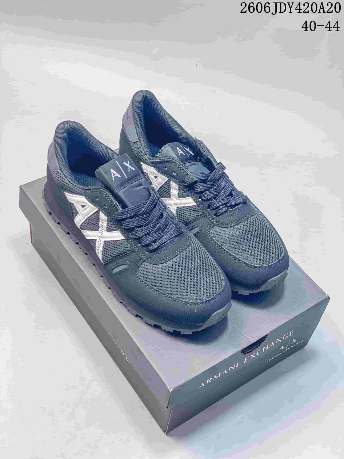 Pair of navy Armani Exchange TREND sneakers with white side logos on a shoebox