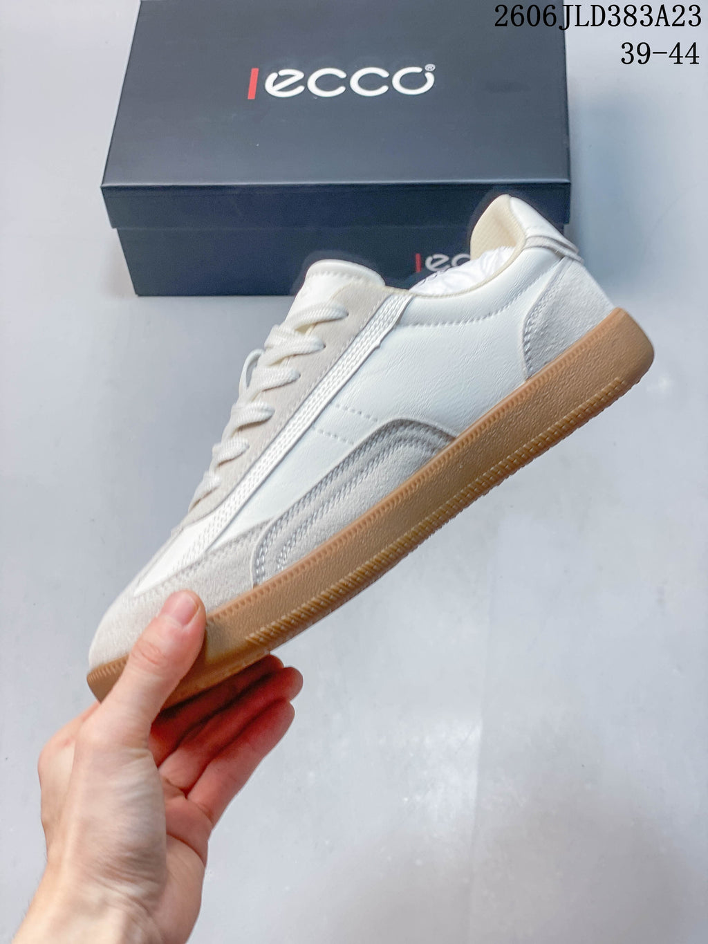 Side view of the white and light gray panelled sneaker with gum-colored outsole