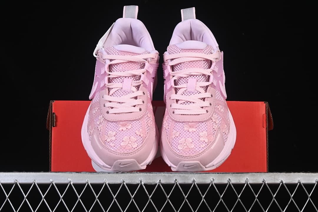 Front view of the pair of pink sneakers displayed on a red shoe box.