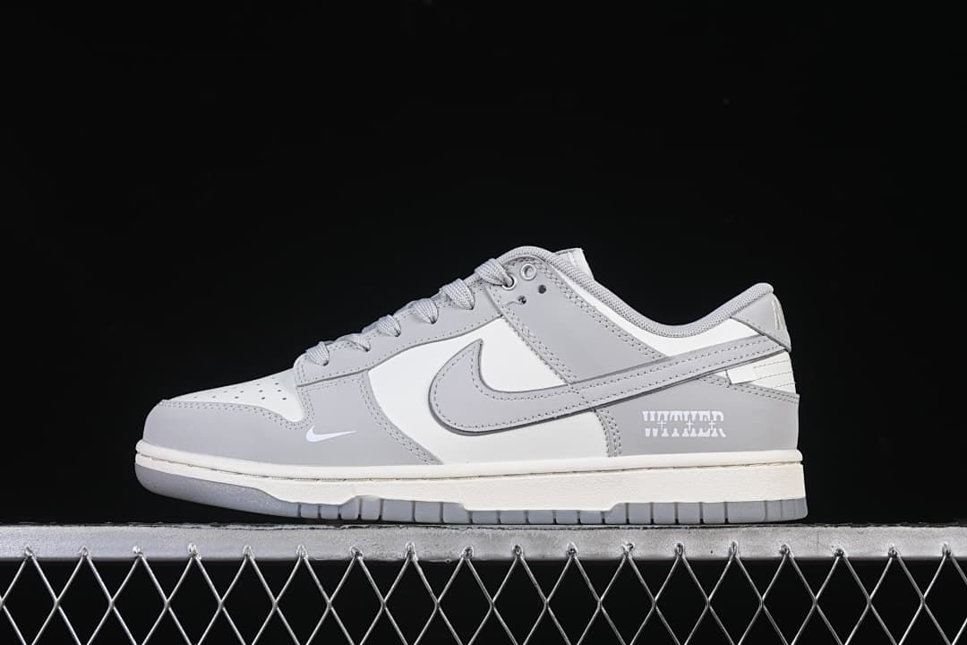 Side view of gray and white Nike SB Dunk Low sneakers on a metal fence.