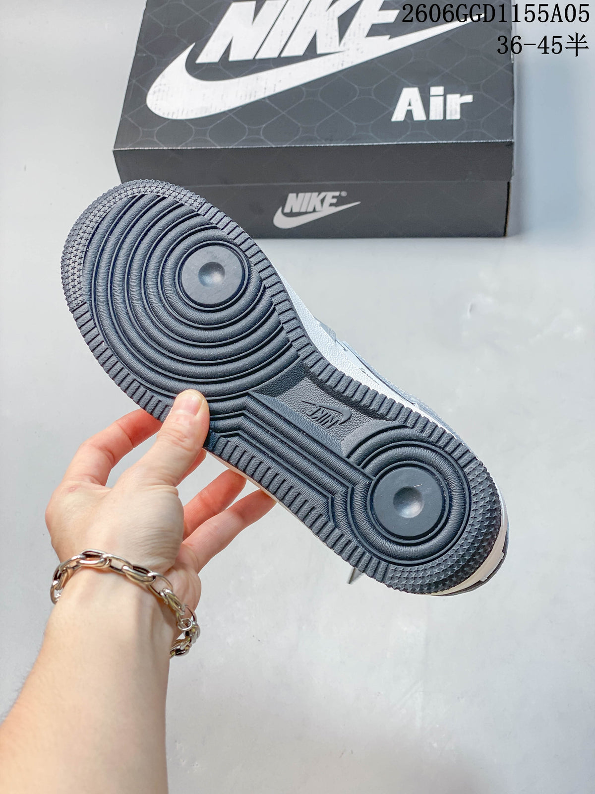 View of the dark textured outsole on a gray and white low-top sneaker