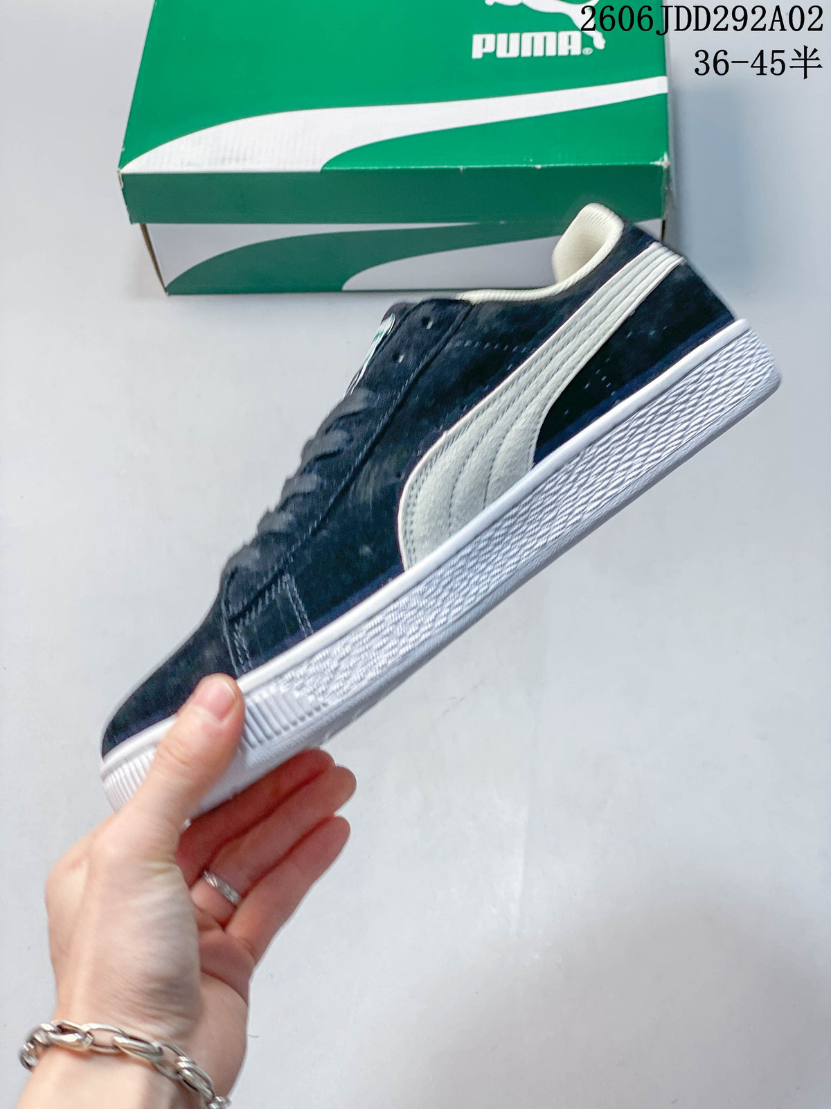 Side view of a navy Puma low-top sneaker with light side detailing and a white sole.