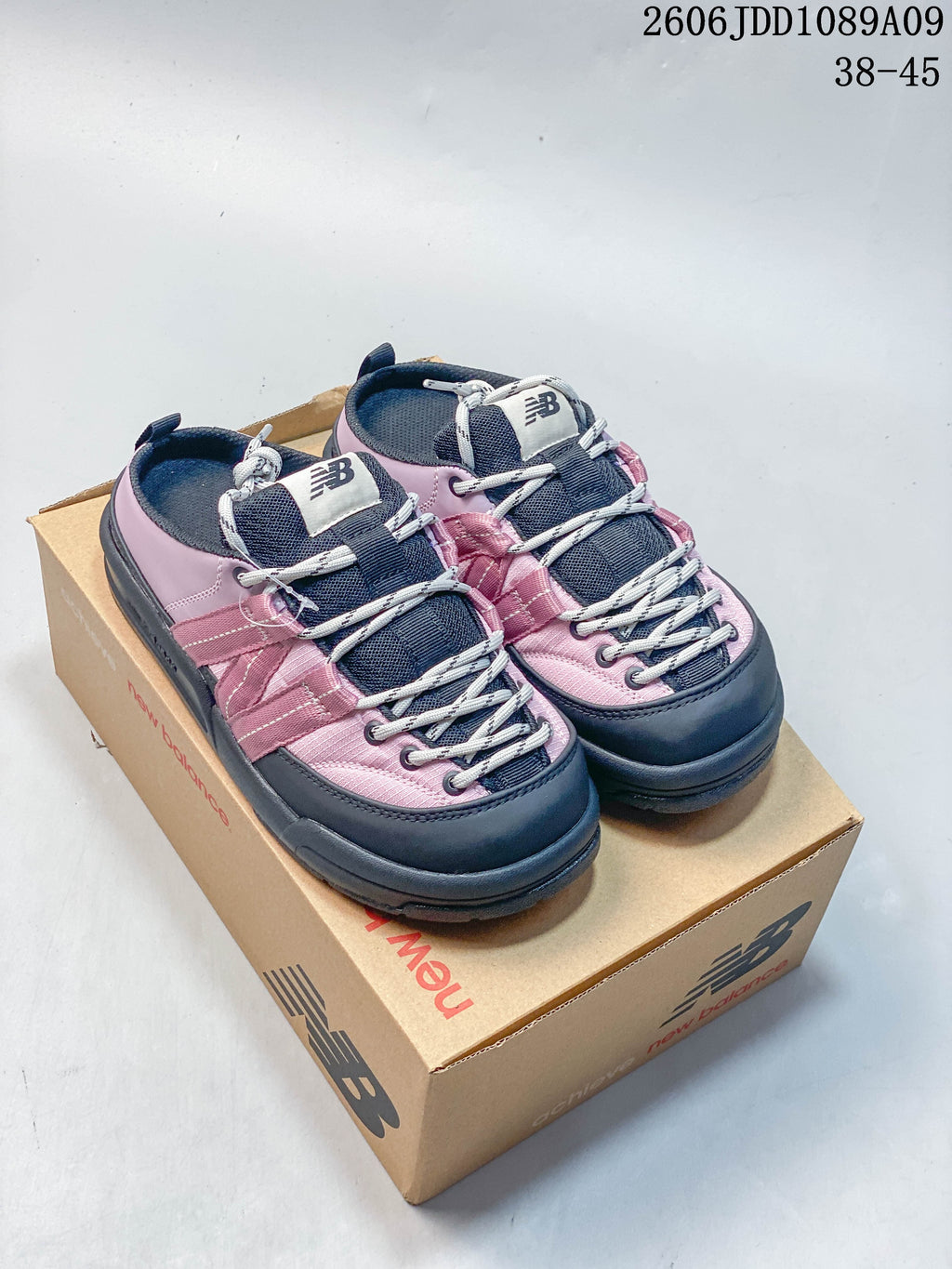 Pink and navy New Balance Terrace Mule shoes shown together on a shoebox.
