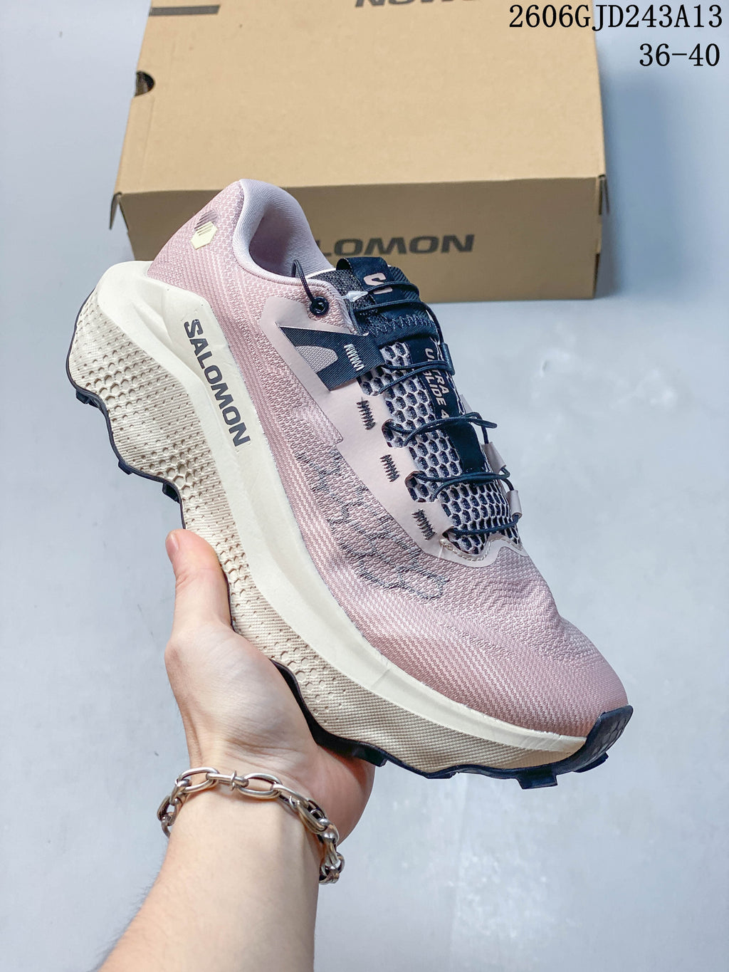 Side view of the pink shoe with Salomon branding and a sculpted light-colored midsole.