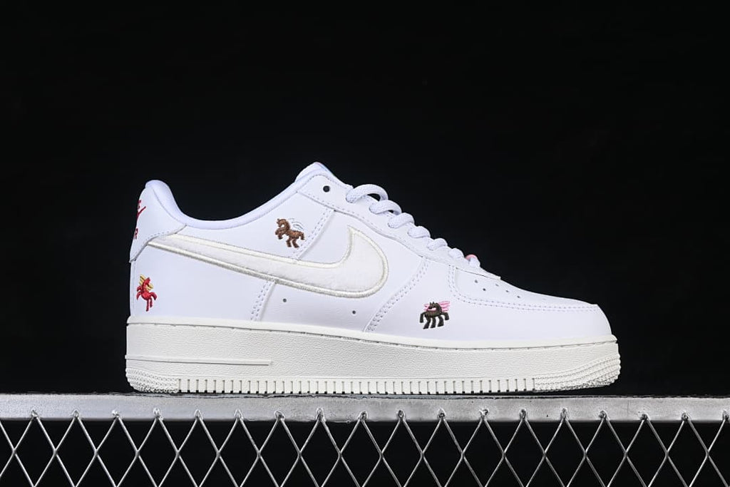 Side view of a white low-top sneaker with a light Swoosh and embroidered horse motifs.