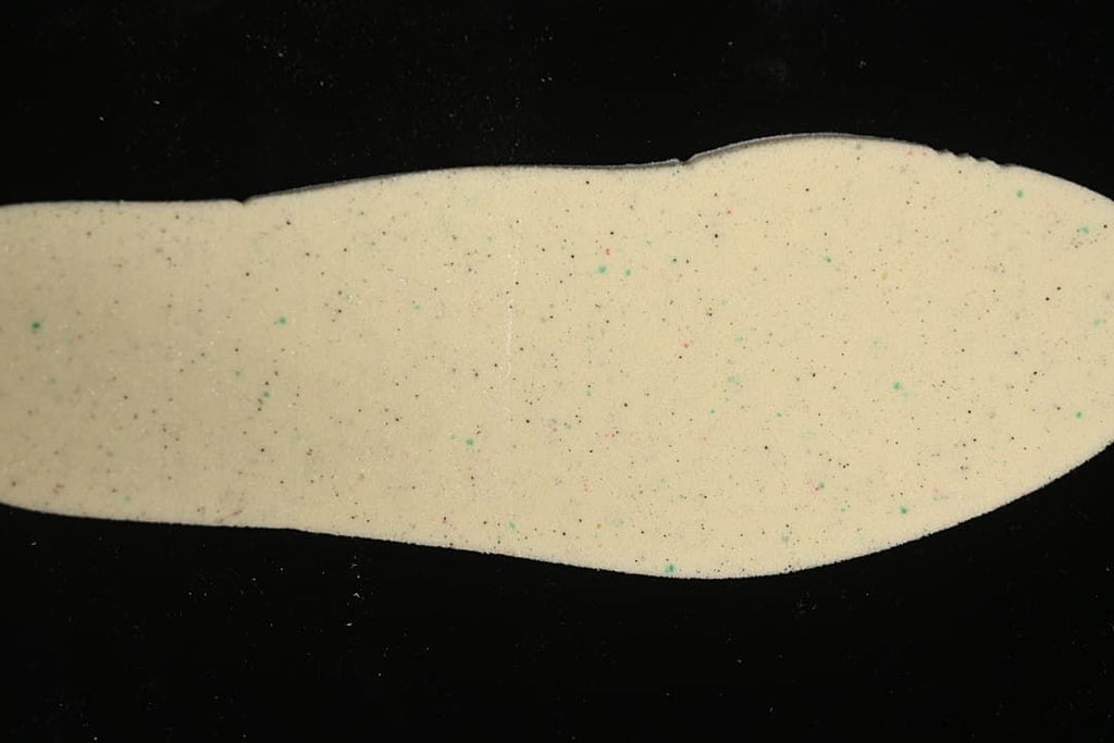 Close-up of a light-colored sneaker insole with small multicolor flecks.