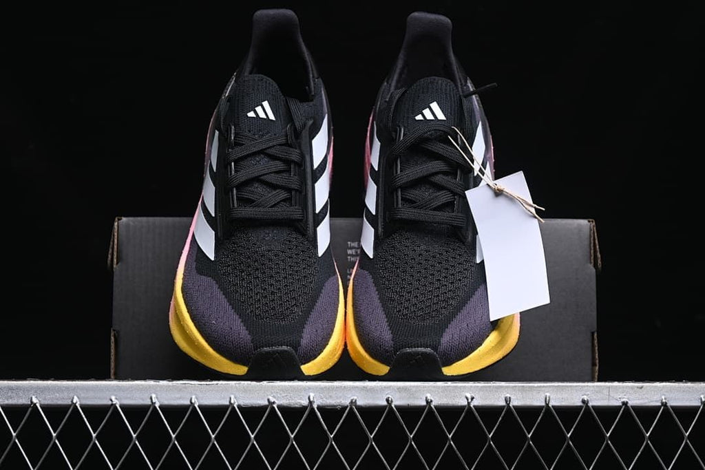 Front view of the pair showing the black uppers, white logos, and yellow toe-side midsole accents.