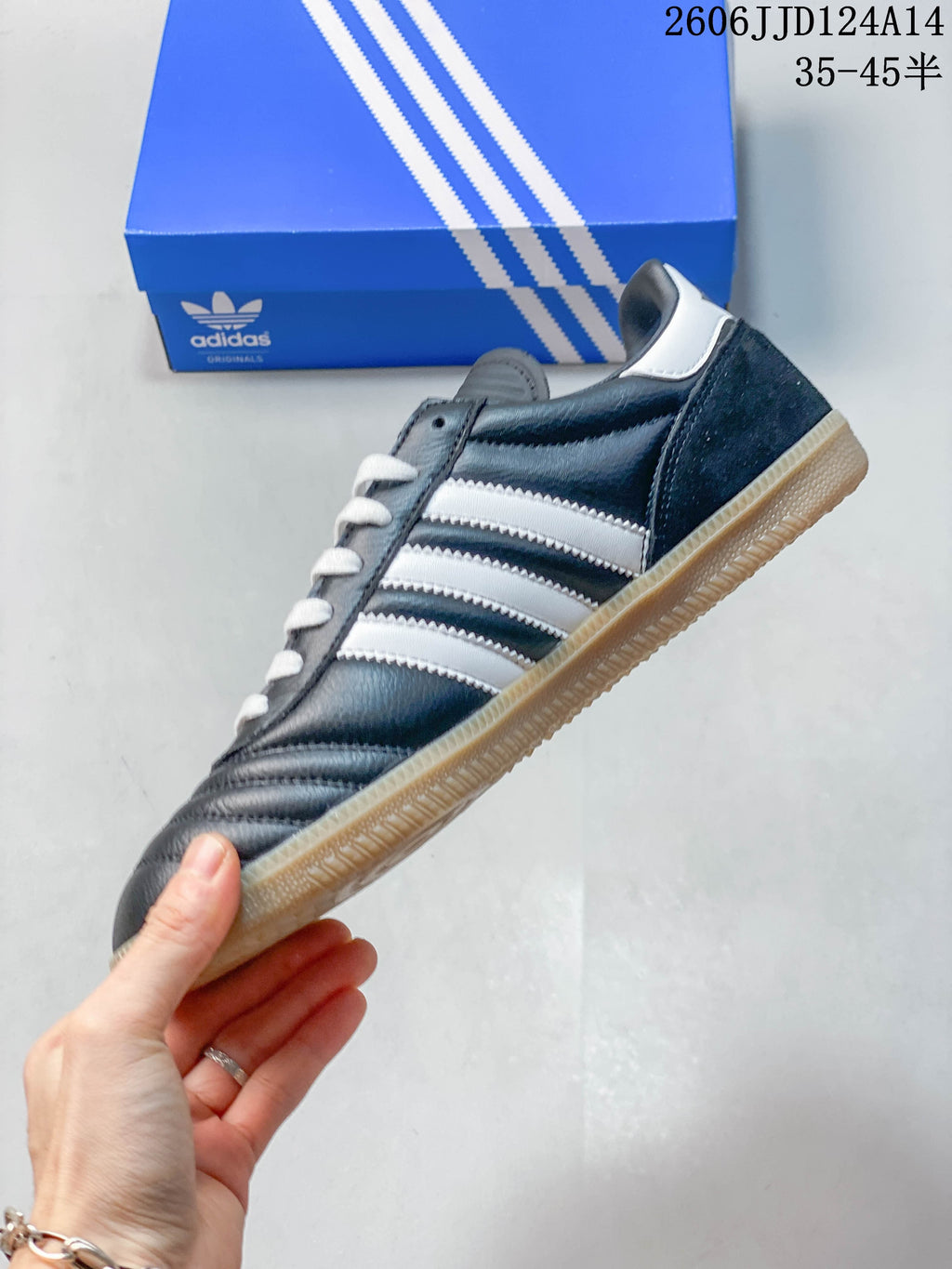 Side view of a dark blue adidas Samba sneaker with white stripes and a gum-colored outsole