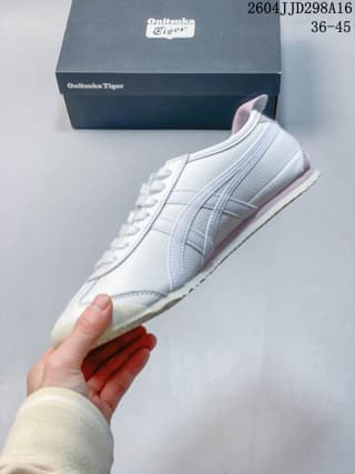 Side view of a white ASICS Tiger Mexico 66 sneaker with light pink accents and a shoe box behind it; overlay shows 2604JJD298A16 and EU size range 36–45.