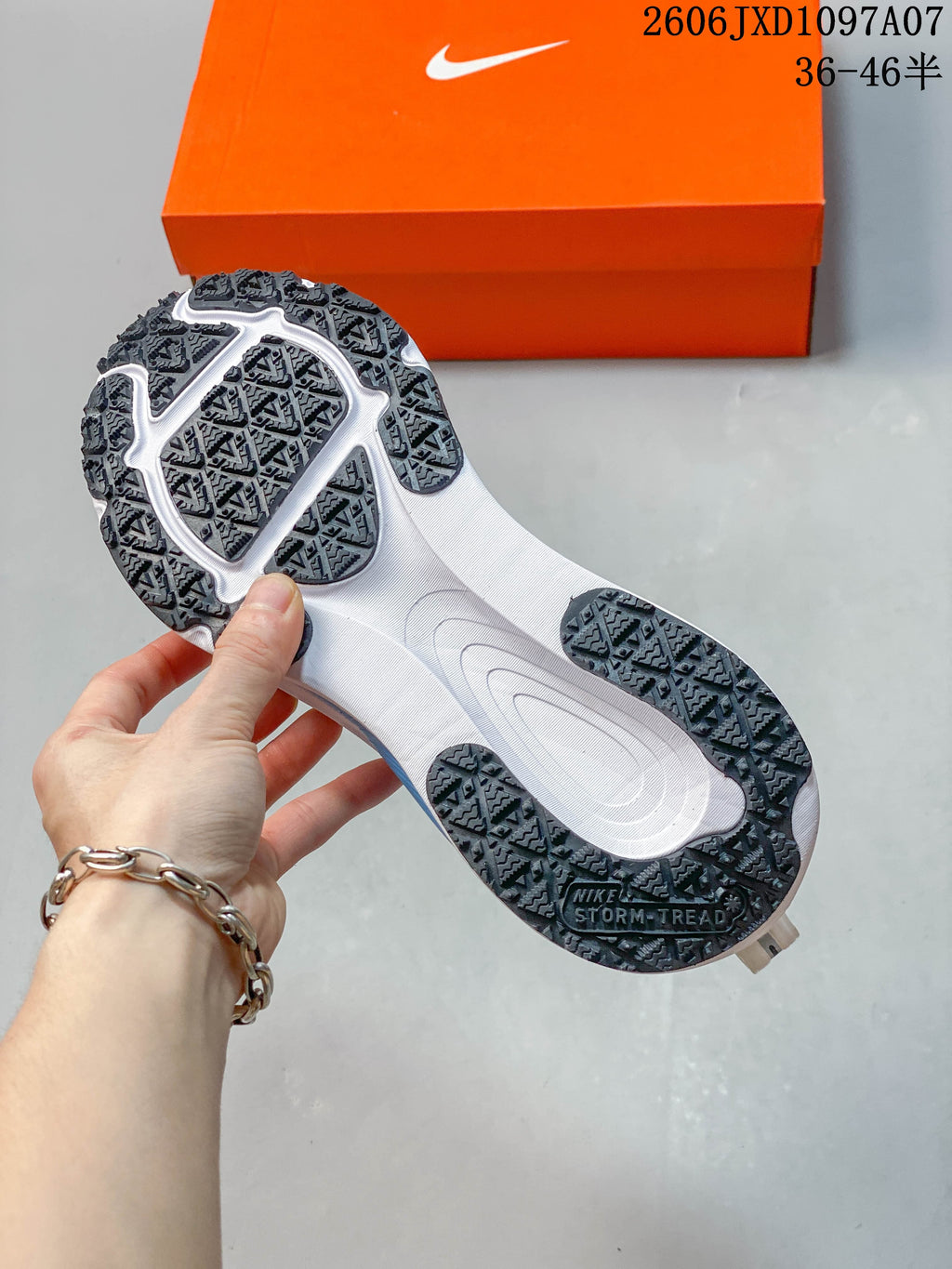 Underside of a shoe showing a dark patterned outsole and white midsole