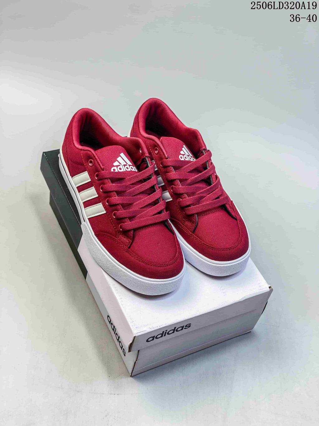Pair of burgundy adidas low-top sneakers with white side stripes and white soles, shown on a shoebox.