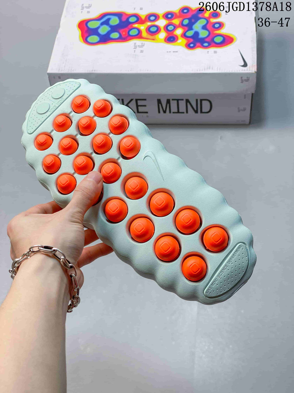 Underside of a Nike Mind slide showing orange circular outsole elements