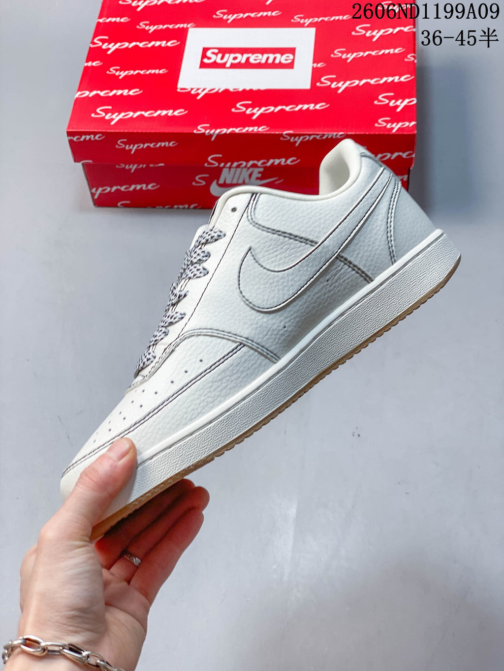 Side view of the white low-top sneaker with outlined Swoosh and gum-colored outsole.
