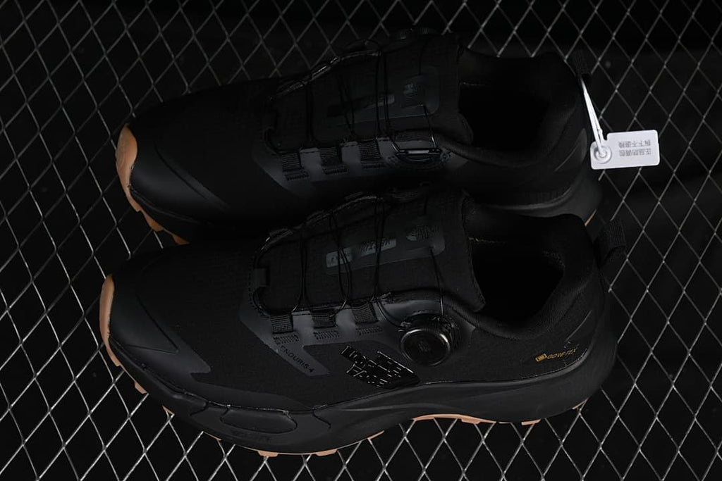 Pair of black low-cut shoes with dial closures and tan-toned outsole accents.