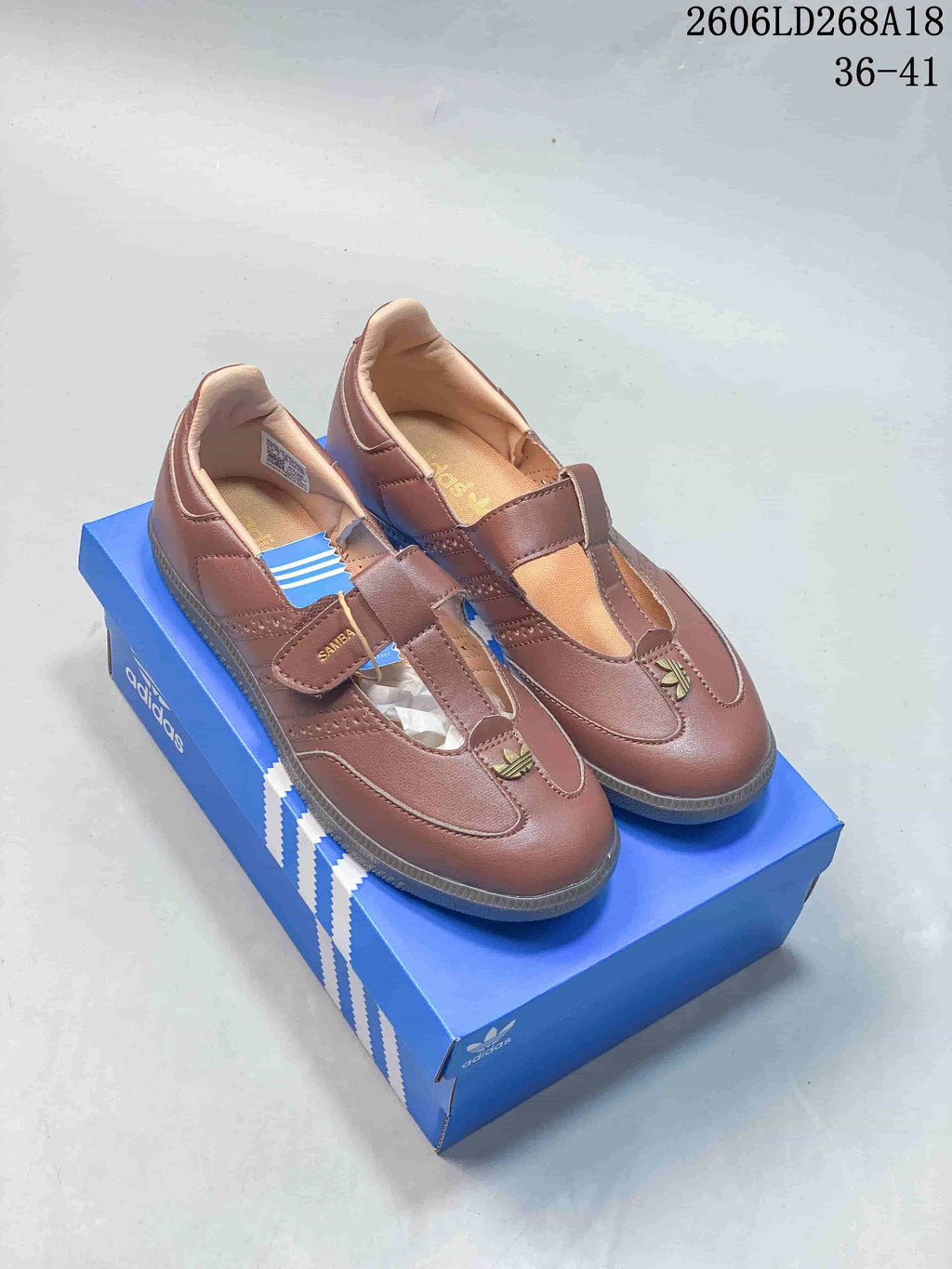 Pair of brown adidas Samba Jane sneakers with Mary Jane-style straps on a blue box