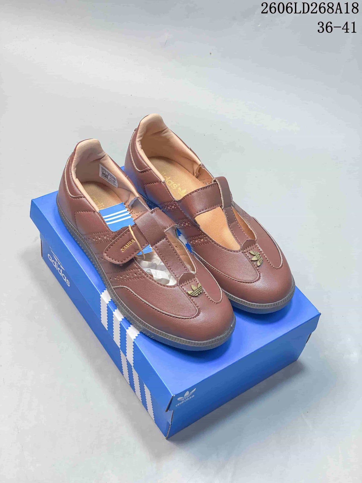 Pair of brown adidas Samba Jane sneakers with Mary Jane-style straps on a blue box