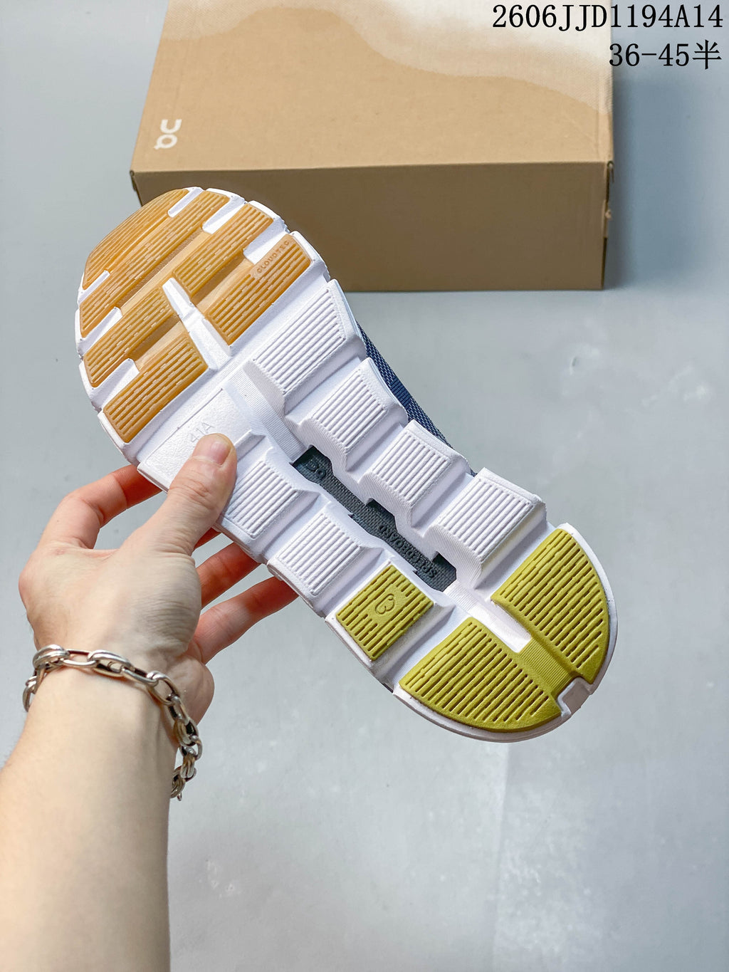 Underside of a blue On Cloud 6 Versa sneaker, showing a white segmented outsole and contrasting tread sections.