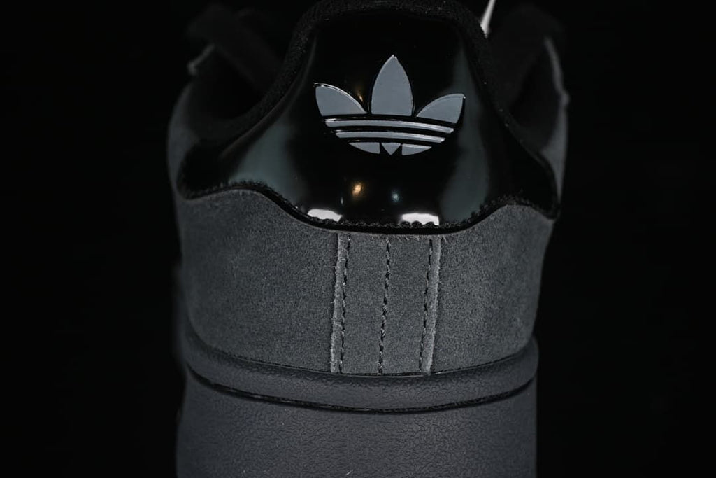 Close-up of the sneaker's glossy black heel tab with trefoil logo