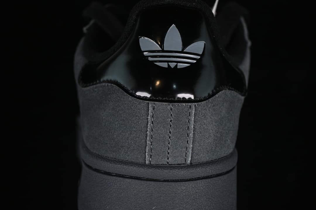 Close-up of the sneaker's glossy black heel tab with trefoil logo