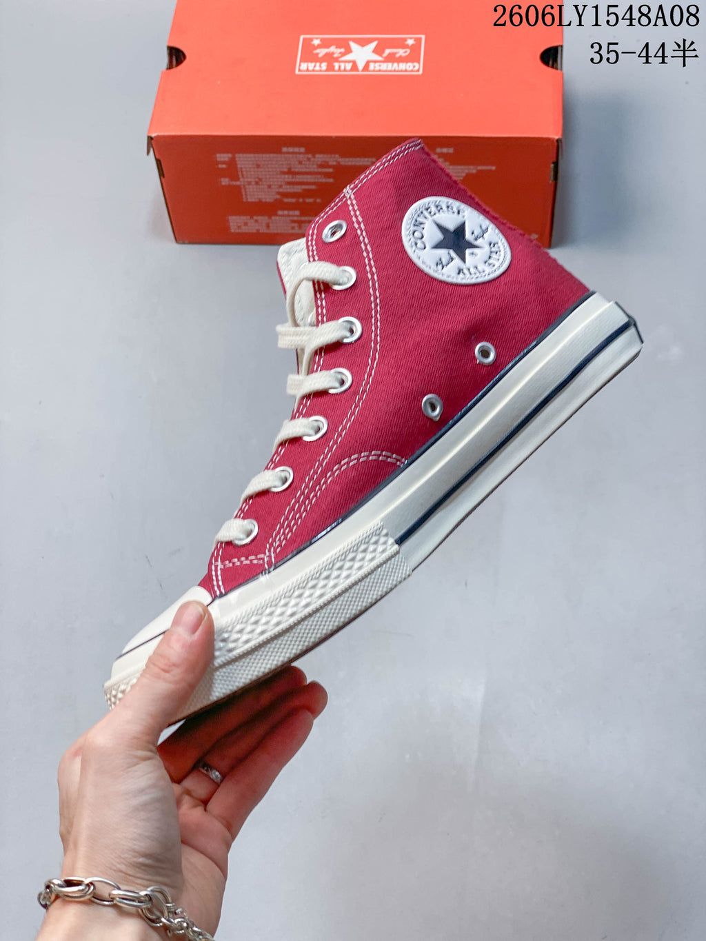 Side view of a red Converse high-top sneaker with white laces, ankle patch, and off-white sole.