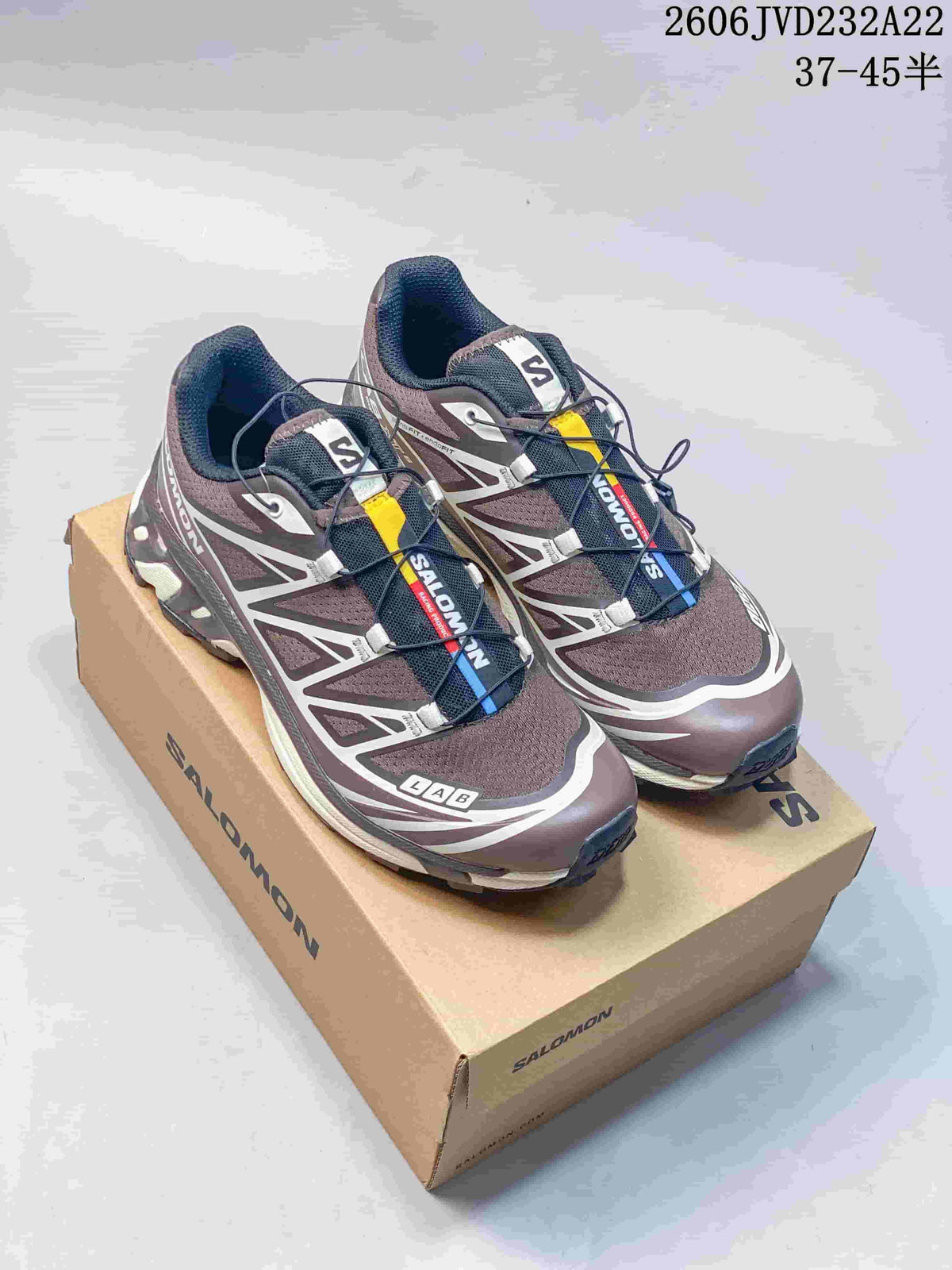Pair of brown and gray Salomon XT-6 shoes on a box, viewed from above at an angle.