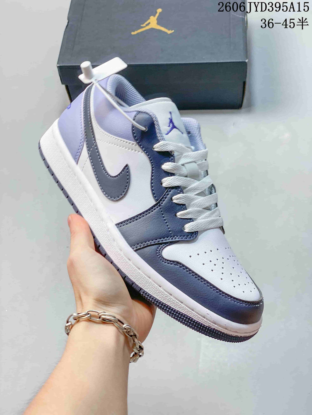 Close-up side view of a white and blue-gray Jordan low-top sneaker held in hand