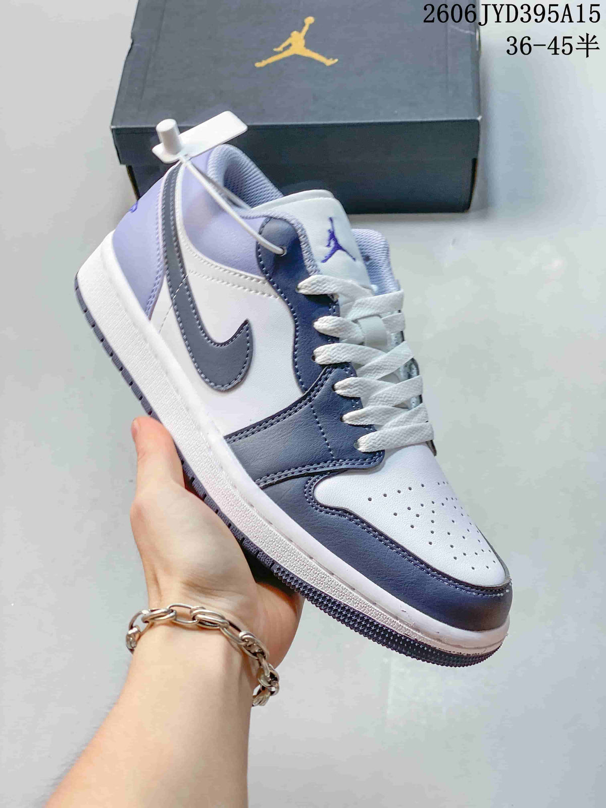 Close-up side view of a white and blue-gray Jordan low-top sneaker held in hand