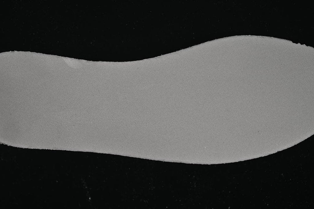 Separate light gray shoe insert shown against a dark background