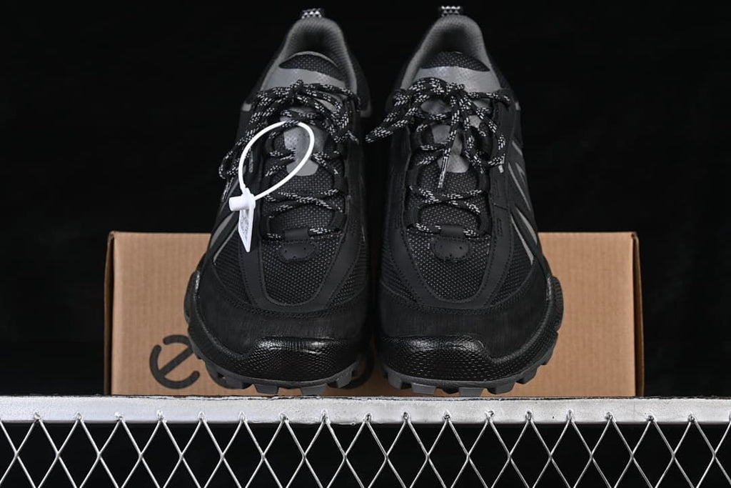 Front view of the pair of black sneakers on a shoe box