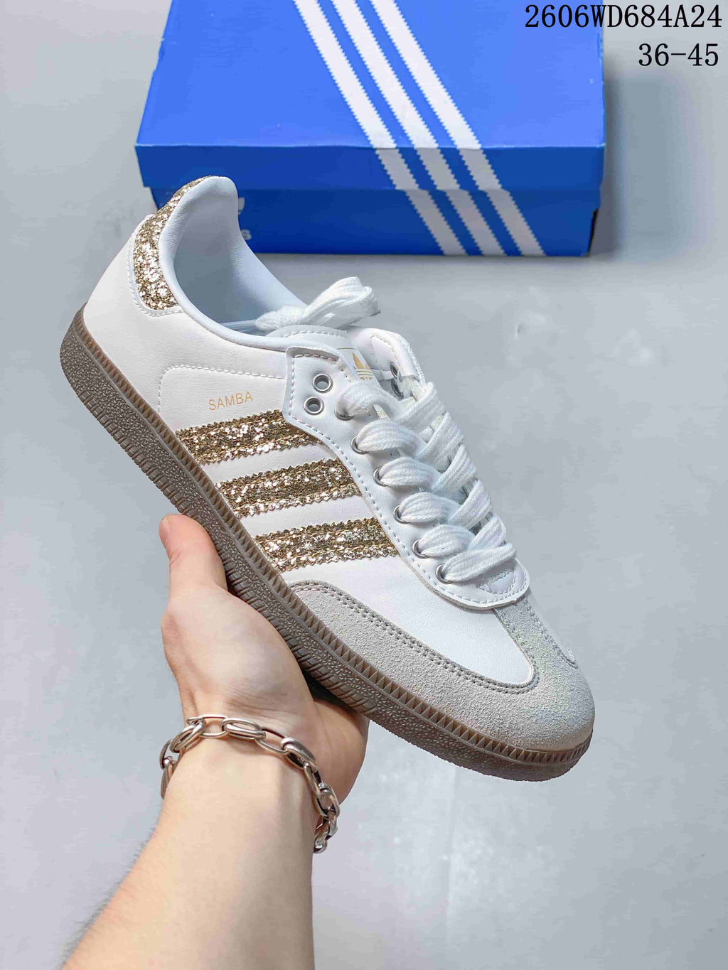 White low-top sneaker with gold glitter-style stripes and gray toe overlay.