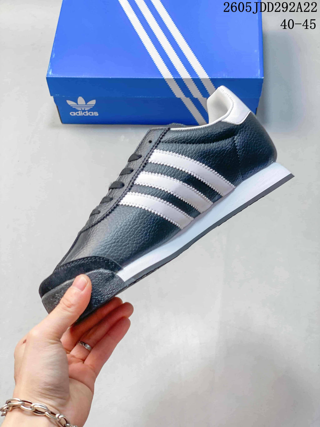 Side view of a charcoal Adidas Samoa sneaker with white stripes and a white midsole