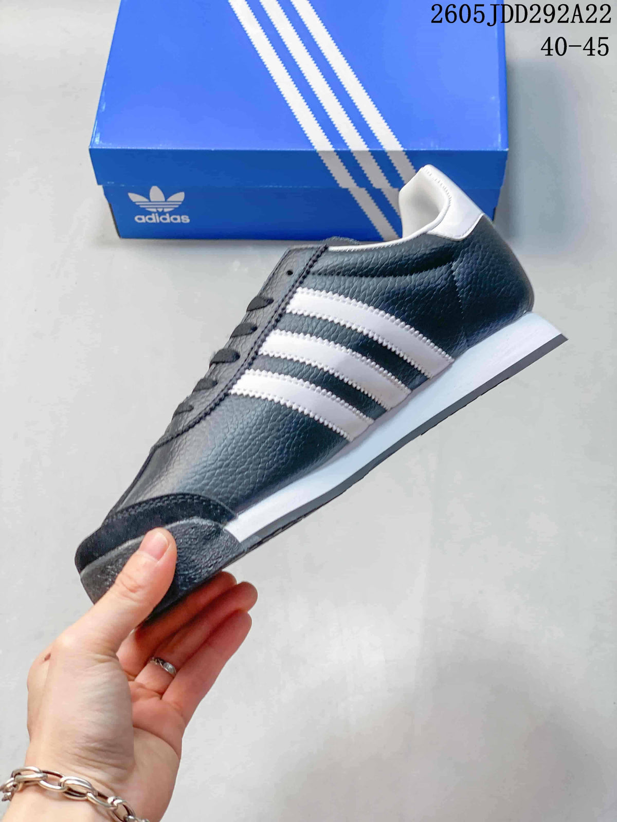Side view of a charcoal Adidas Samoa sneaker with white stripes and a white midsole