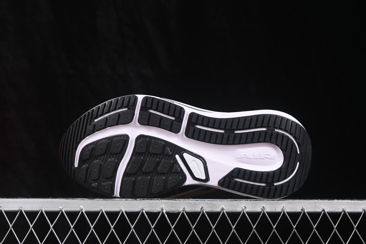 Bottom view of black and white Nike running sneakers showing the segmented rubber outsole and traction pattern.