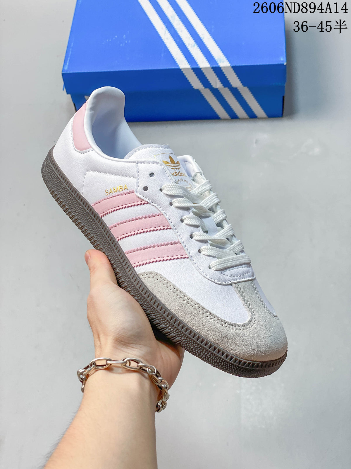 Angled side view of a white adidas Samba OG sneaker with pink stripes, light beige toe overlay, and dark gum-colored outsole.
